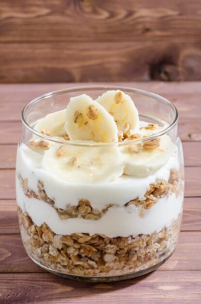 Muesli con yogurt naturale, banana, frutta secca e frutta secca in un barattolo di vetro