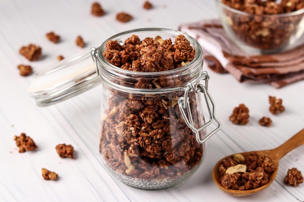 Muesli croccante di muesli con miele naturale, cioccolato e noci in un barattolo di vetro su uno sfondo chiaro, cibo sano, primo piano, orientamento orizzontale