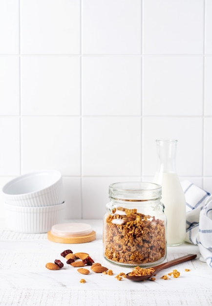 Muesli di avena con noci e frutta secca per preparare una sana colazione su un luminoso tavolo da cucina. Stile scandinavo bianco. Messa a fuoco selettiva.