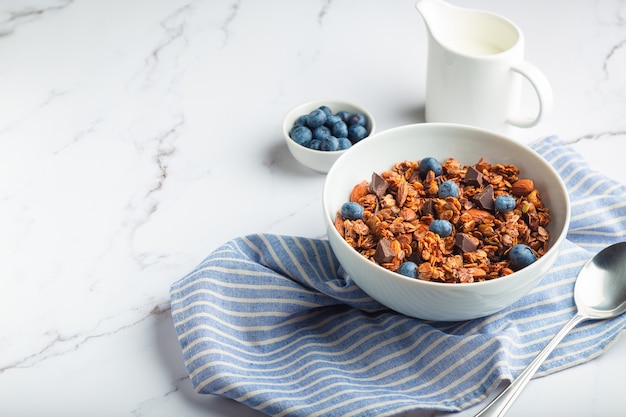 muesli di muesli fatti in casa con pezzi di cioccolato fondente noci e mirtilli in una ciotola