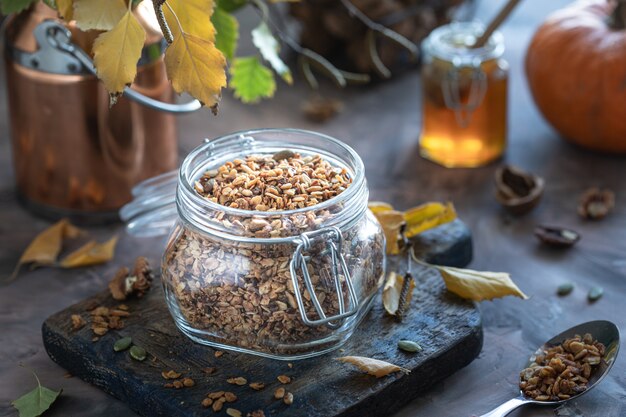 Muesli di zucca fatti in casa con noci e semi in un barattolo di vetro per una sana colazione. Natura morta autunnale