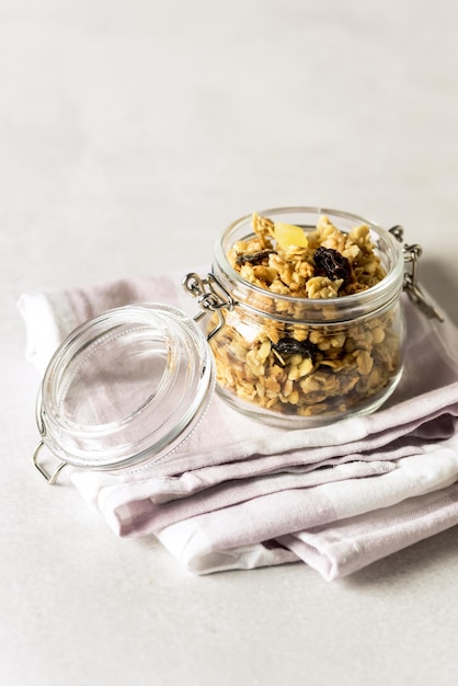 Muesli fatti in casa in un barattolo di vetro su sfondo grigio tovagliolo Cibo dietetico sano verticale