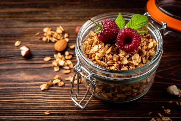 Muesli in vaso di vetro e lampone sul tavolo di legno scuro