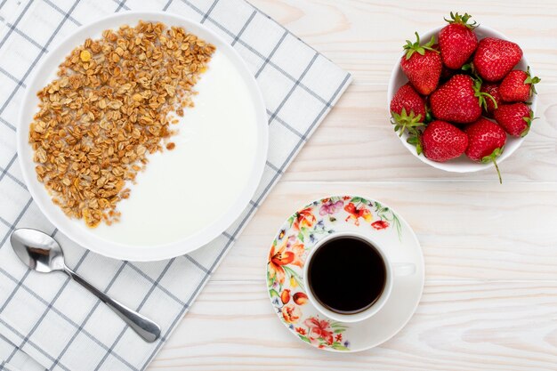 muesli, una tazza di caffè nero e fragola su un tavolo di legno