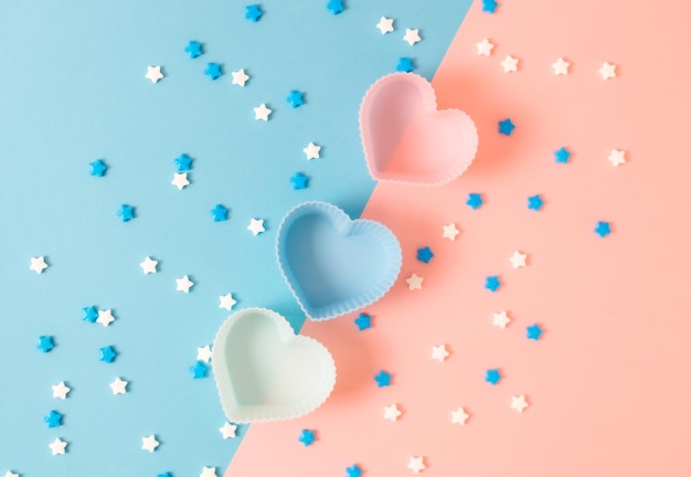 Muffin a forma di cuore e granelli di caramelle su rosa e blu