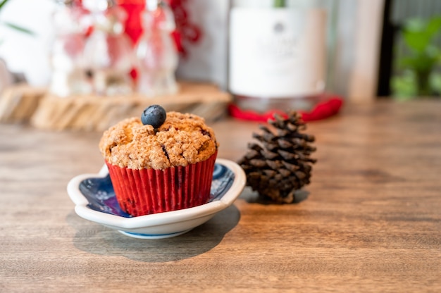 Muffin ai mirtilli al forno fatti in casa sul piatto con pigna al tavolo di legno