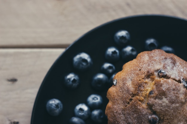 Muffin ai mirtilli con zucchero a velo e frutti di bosco freschi.