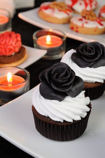 Muffin al cioccolato con crema decorato con rosa proteica nera di marzapane