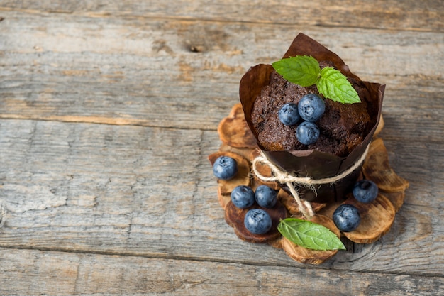 Muffin al cioccolato con menta e mirtilli su supporto in legno Copia spazio