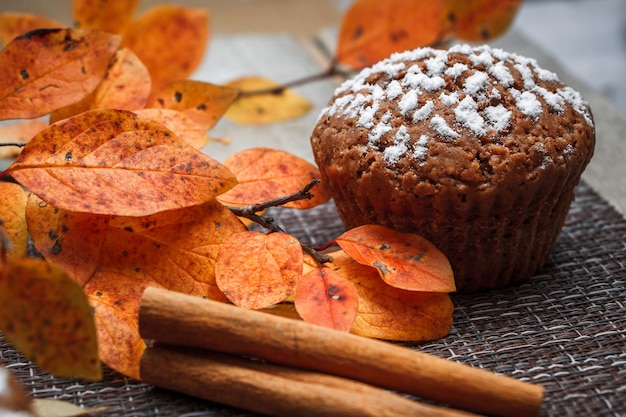 Muffin al cioccolato con ripieno di mele su uno sfondo di foglie autunnali e cannella