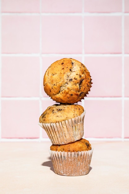 Muffin al cioccolato e banana in pila sparata su sfondo colorato luce dura verticale