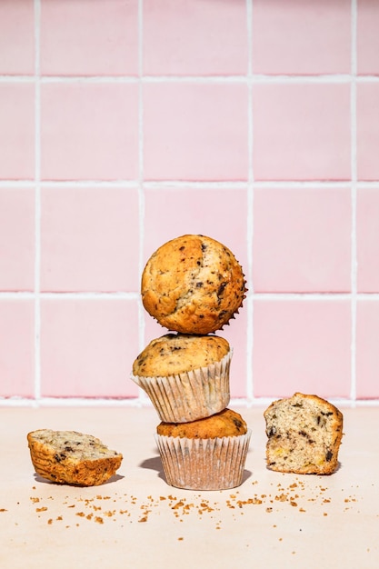 Muffin al cioccolato e banana in pila sparata su sfondo colorato luce dura verticale