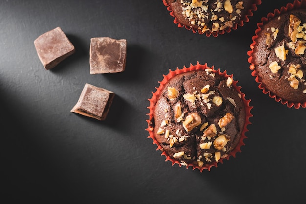 Muffin al cioccolato fatti in casa o cupcakes cosparsi di noci su sfondo scuro vista dall'alto