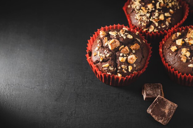 Muffin al cioccolato fatti in casa o cupcakes cosparsi di noci su sfondo scuro