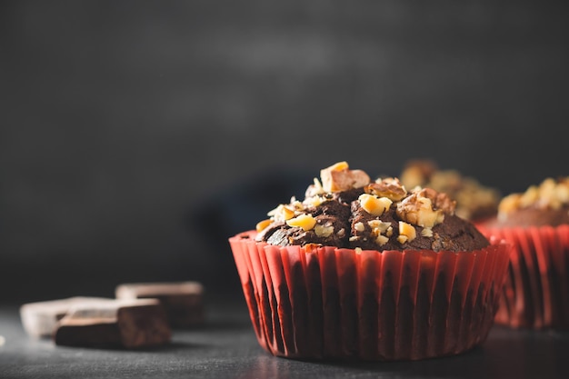 Muffin al cioccolato fatti in casa o cupcakes cosparsi di noci su sfondo scuro