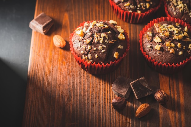 Muffin al cioccolato fatti in casa o cupcakes cosparsi di noci su una tavola di legno