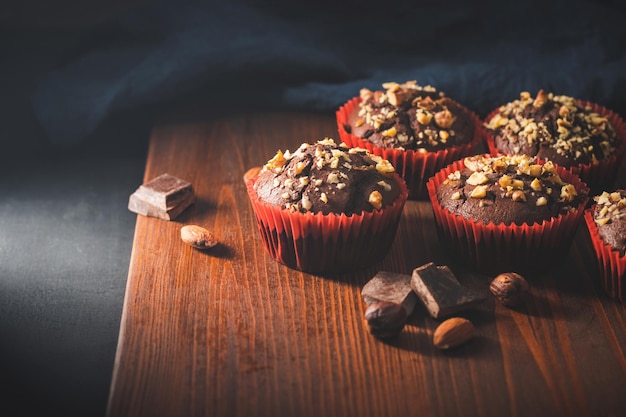 Muffin al cioccolato fatti in casa o cupcakes cosparsi di noci su una tavola di legno