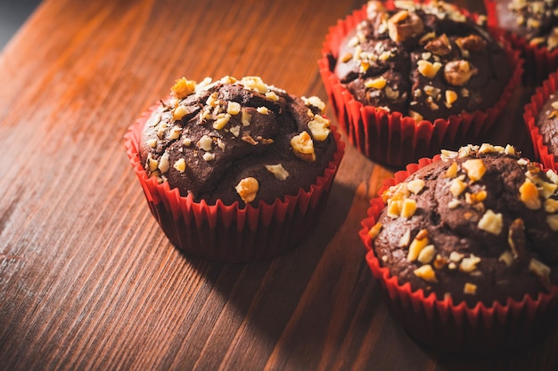 Muffin al cioccolato fatti in casa o cupcakes cosparsi di noci su una tavola di legno