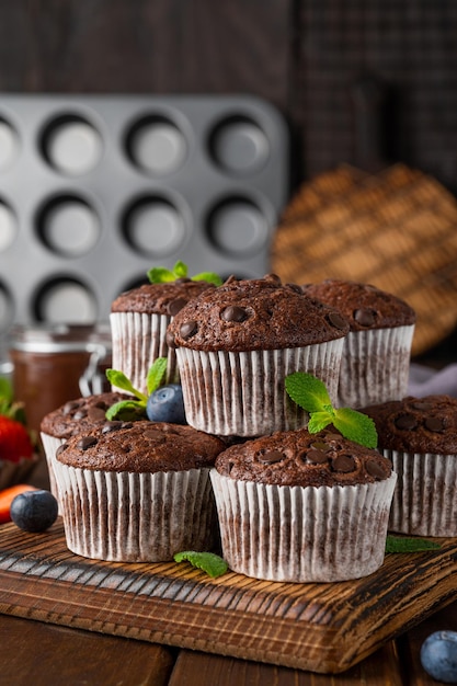 Muffin al cioccolato o cupcakes con gocce di cioccolato con frutti di bosco freschi e menta Copia spazio