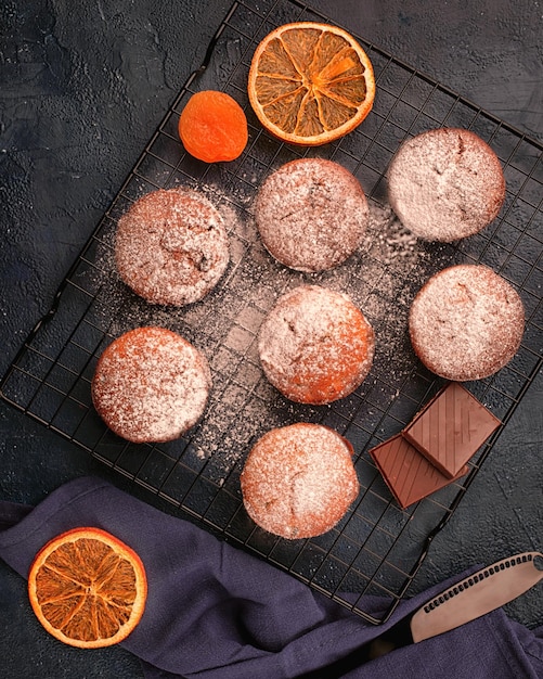 Muffin al cioccolato su griglia di raffreddamento decorati su sfondo nero Vista dall'alto