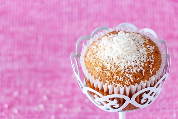 Muffin alla vaniglia fatto in casa con polvere di cocco Sfondo rosa Copia spazio Messa a fuoco selettiva