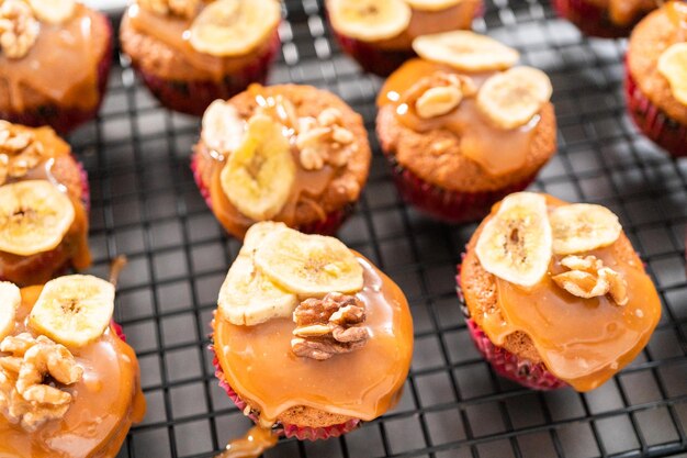 Muffin appena sfornati di pane alle noci e banana conditi con caramello fatto in casa, decorati con noci e chips di banana.