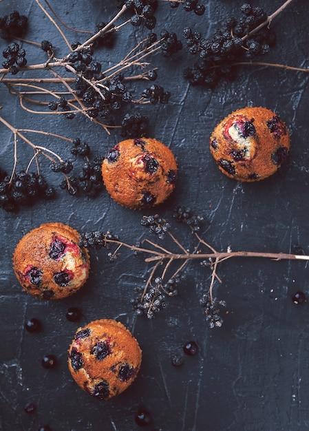 Muffin con ribes su uno sfondo scuro accanto alle bacche sui rami. in stile rustico. stile scuro