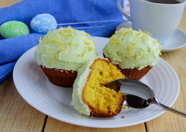 Muffin di cupcakes al limone chiaro su fondo in legno e una tazza di tè.