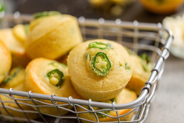 Muffin di pane di mais appena sfornati con peperoncino jalapeno piccante in cestello metallico.