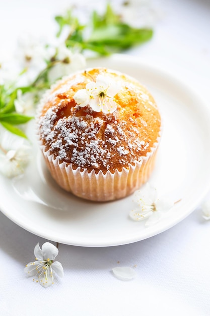 Muffin dolci con zucchero a velo e fiori Panetteria fatta in casa Muffin in capsule bianche decorate con fiori di alberi da frutto