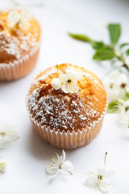 Muffin dolci con zucchero a velo e fiori Panetteria fatta in casa Muffin in capsule bianche decorate