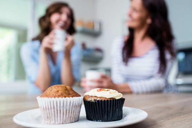 Muffin e cupcake serviti sul tavolo con gli amici seduti in background