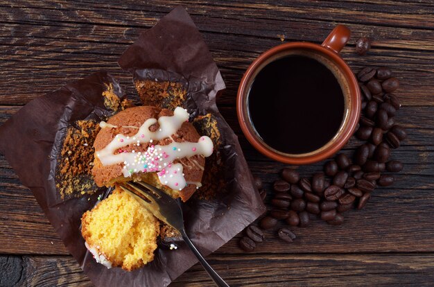 Muffin e fetta in carta marrone con tazza di caffè sul tavolo in legno scuro, vista dall'alto