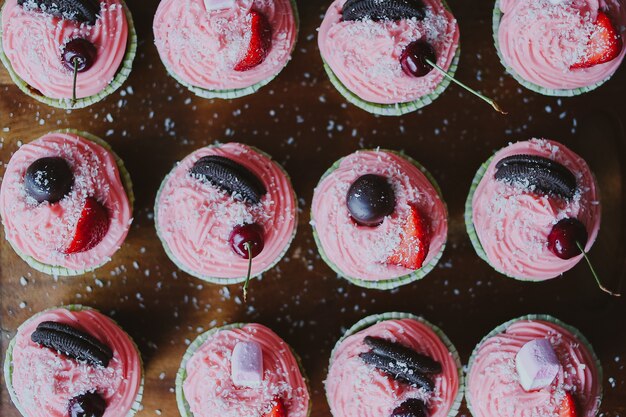 Muffin fatti in casa, cappkake con fragole, ciliegia e crema rosa