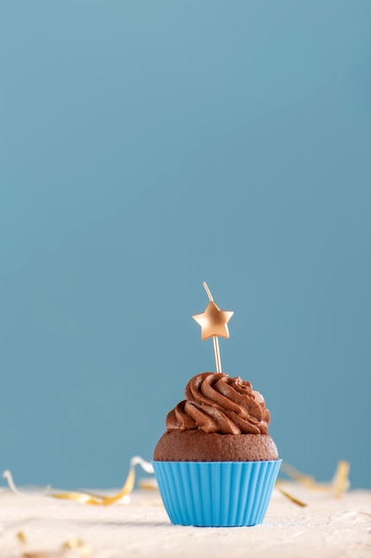 Muffin fatti in casa con glassa al burro di cioccolato con candela a forma di stella su sfondo blu Cornice verticale