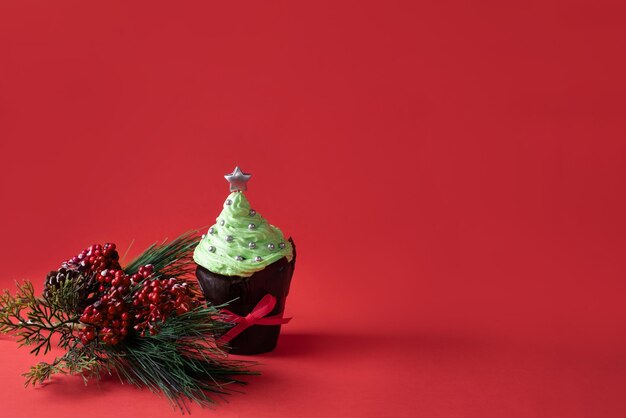 Muffin festivo, cupcake di Natale con parte superiore crema verde e stella su sfondo rosso, spazio copia.