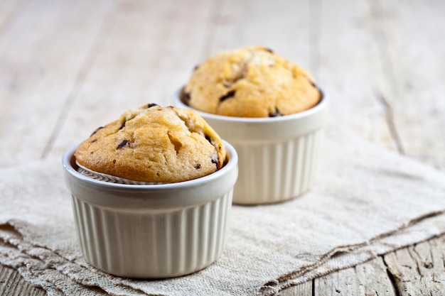 Muffin freschi fatti in casa su ciotole di ceramica bianca sul tovagliolo di lino.