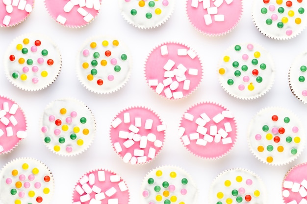 Muffin graziosamente decorati variopinti multipli su un fondo bianco