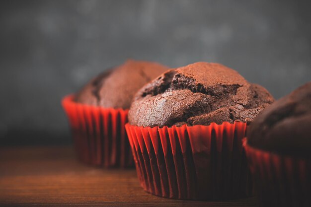 Muffin o cupcakes al cioccolato fatti in casa su un tavolo di legno e uno sfondo scuro