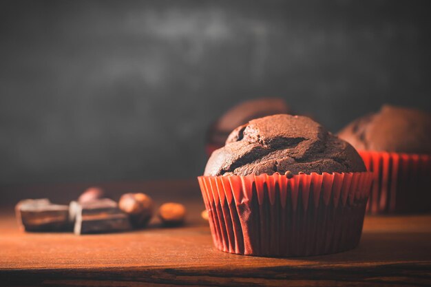 Muffin o cupcakes al cioccolato fatti in casa su un tavolo di legno e uno sfondo scuro