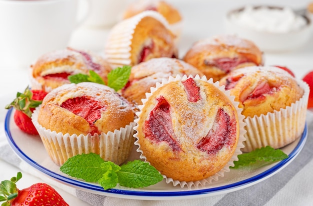 Muffin o cupcakes alla fragola fatti in casa su un piatto su uno sfondo di legno bianco Messa a fuoco selettiva