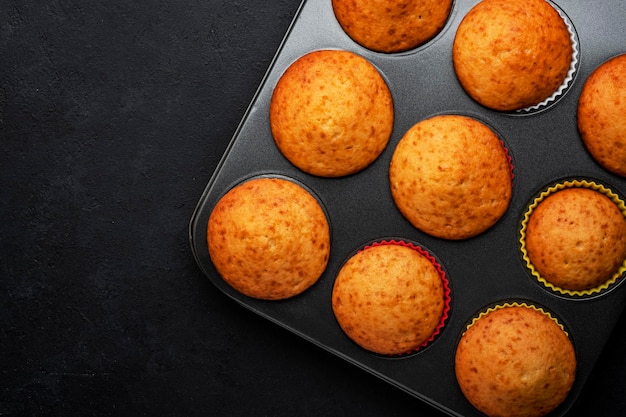 Muffin o cupcakes arancioni appetitosi su sfondo nero della tavola Dolci fatti in casa invernali vista dall'alto