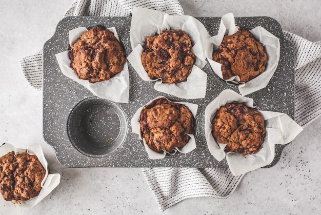 Muffin sani della bacca del vegano in un piatto di cottura su un fondo bianco.