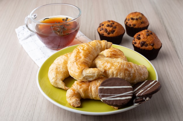 Muffin, tazza di tè, croissant e biscotti al caramello