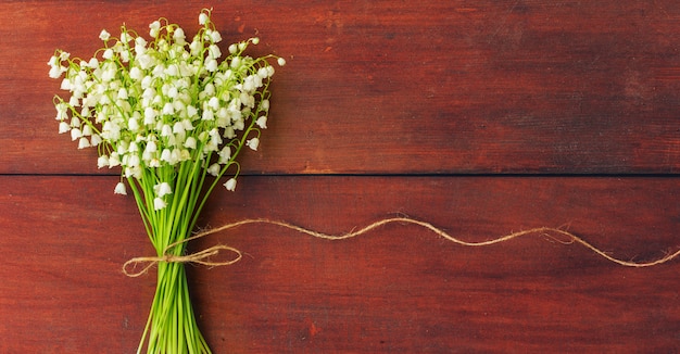 Mughetti dei fiori bianchi sui bordi di legno marroni. copyspace. Spazio libero per il testo