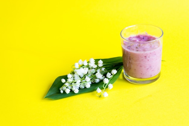 Mughetto. Frullato di bacche fresche su un giallo. Mughetti e frullati di frutti di bosco. Primavera