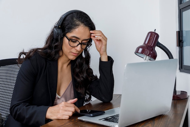 Mujer aburrida revisando sus mensajes de celular mientras trabaja desde casa por la cuarentena