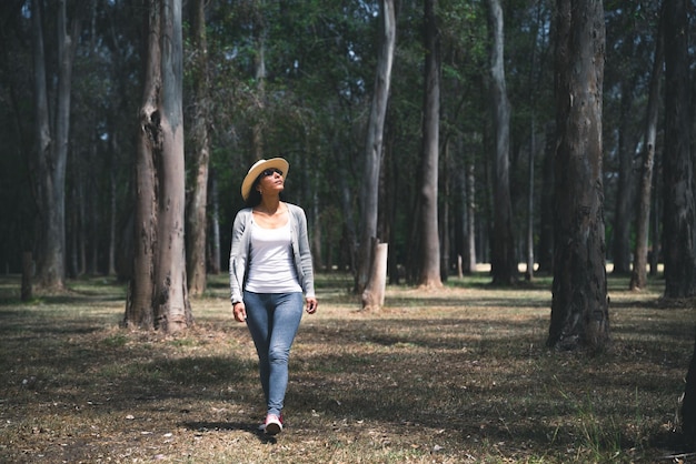 Mujer con sombrero caminado en bosque