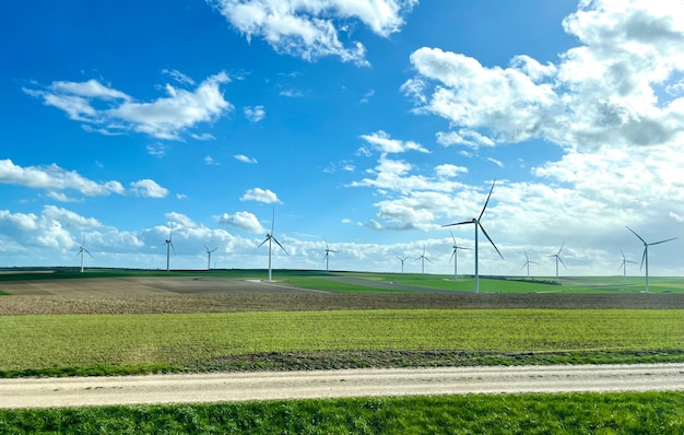 Mulini a vento sullo sfondo di un campo verde e un cielo nuvoloso blu