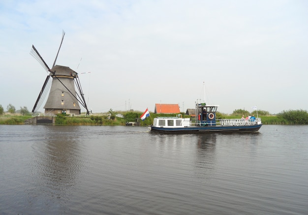 Mulino a vento e barca olandesi tradizionali sul canale a Kinderdijk, Molenwaard, Paesi Bassi